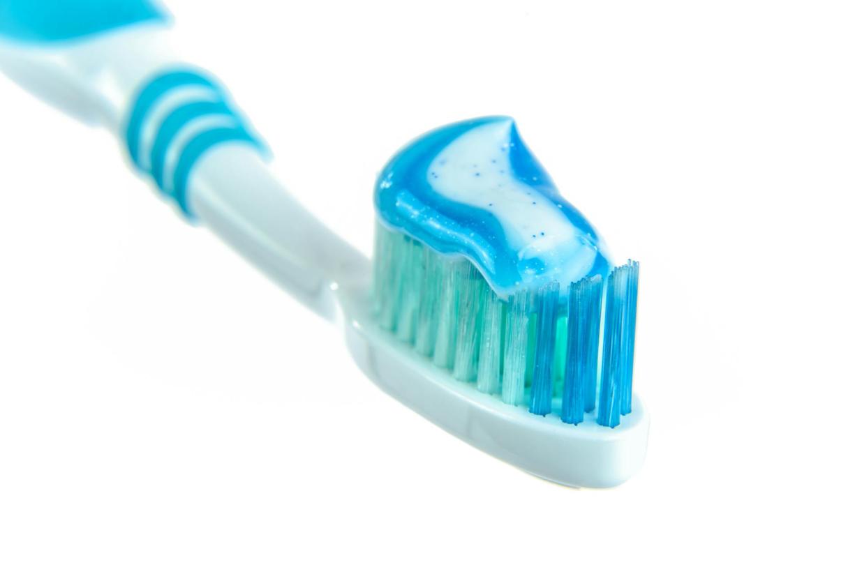 close up of a teal and white toothbrush with toothpaste on it