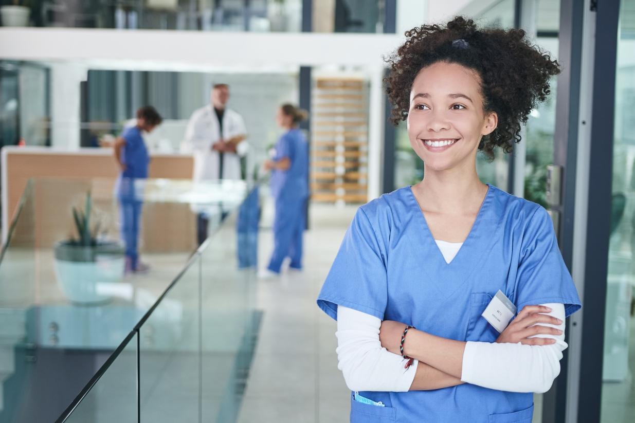 Female dental professional smiling with arms crossed and looking off into the distance.