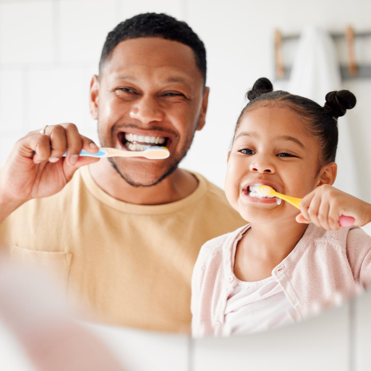Father and daughter brushing their teeth together.