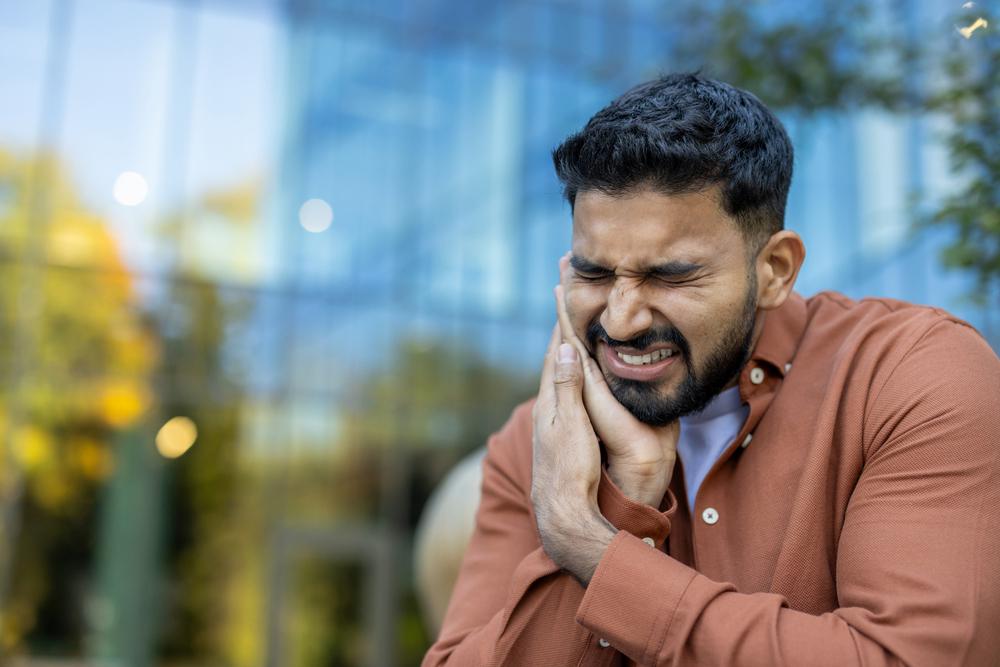 Man holding onto face in pain