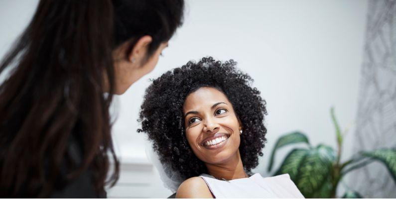 A patient smiles up at another person from a dentist chair
